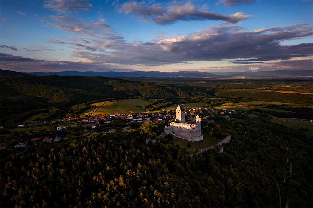 Letecký pohľad na Topoľčiansky hrad a okolitú krajinu v podvečernom svetle.