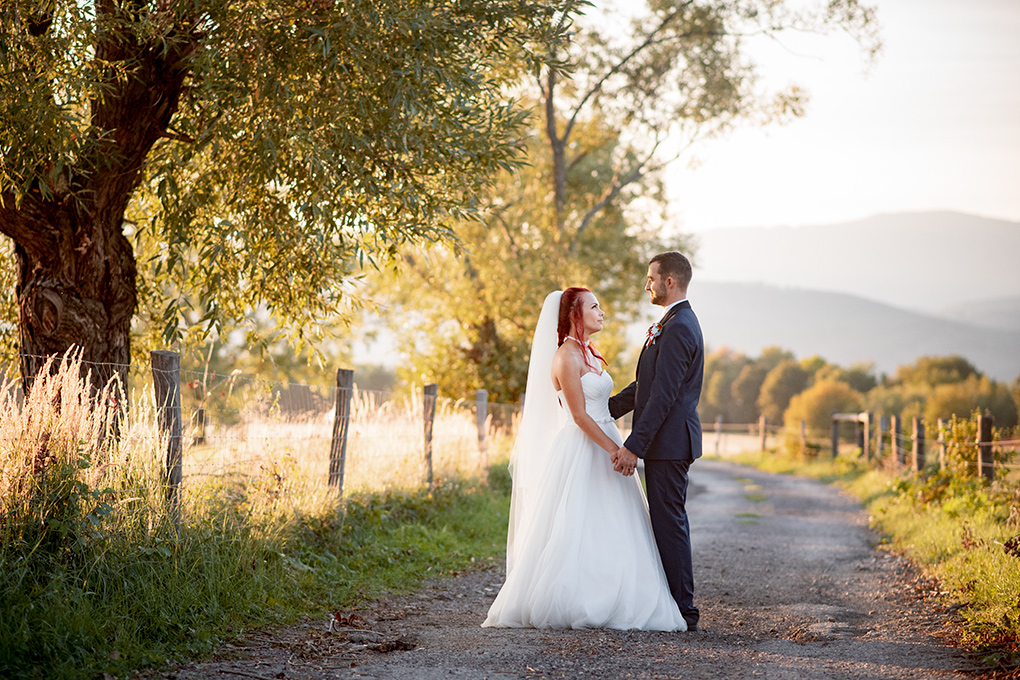 Nevesta a ženích na poľnej ceste v teplom podvečernom svetle