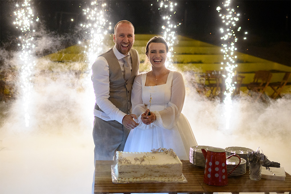 Nevesta so ženíchom pri svadobnej torte medzi studenými iskrami a plazivým dymom na Ranch 13.