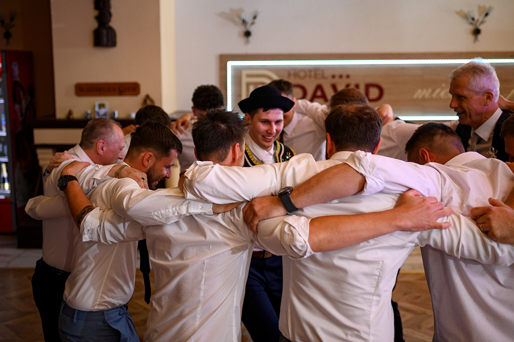 Svadobní hostia a muži vytvárajú tesný tanečný kruh okolo ženícha Martina.