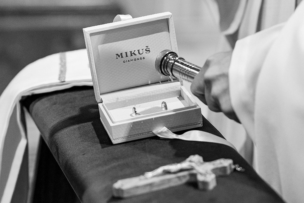 Kňaz požehnáva svadobné obrúčky v krabičke.