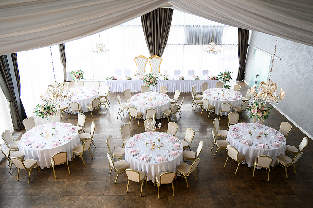 Prestreté okrúhle stoly v svadobnej sále pred hostinou.