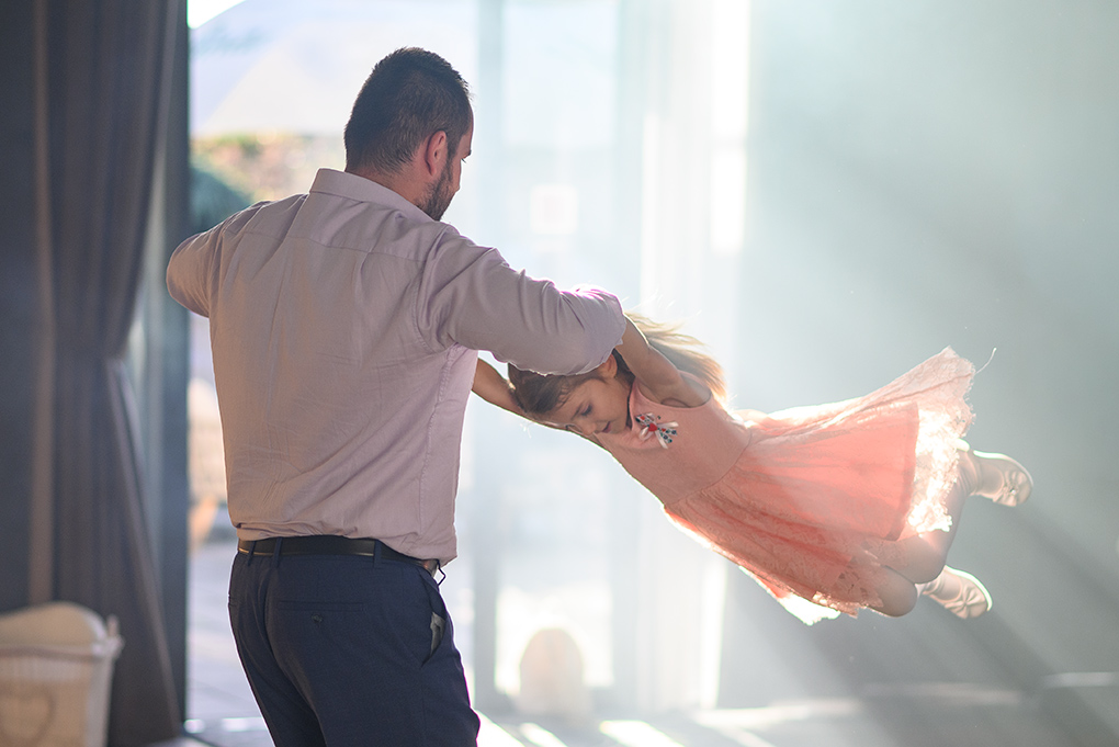 Otec točí malú družičku na parkete.