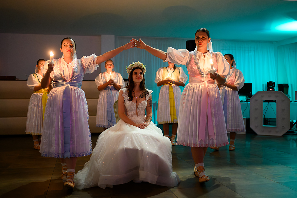 Ženy v krojoch so sviečkami v sále Madonna Mia.