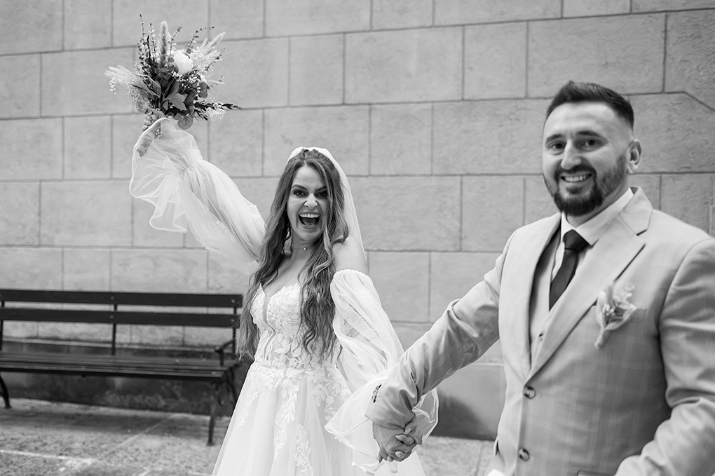 Odchod novomanželov Pár odchádza z obradu s kyticou nad hlavou pred hradbami zámku.