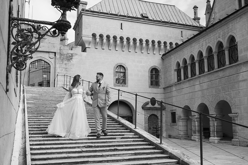 Pár na nádvorí Čiernobiely záber páru držiacich sa za ruky na nádvorí.