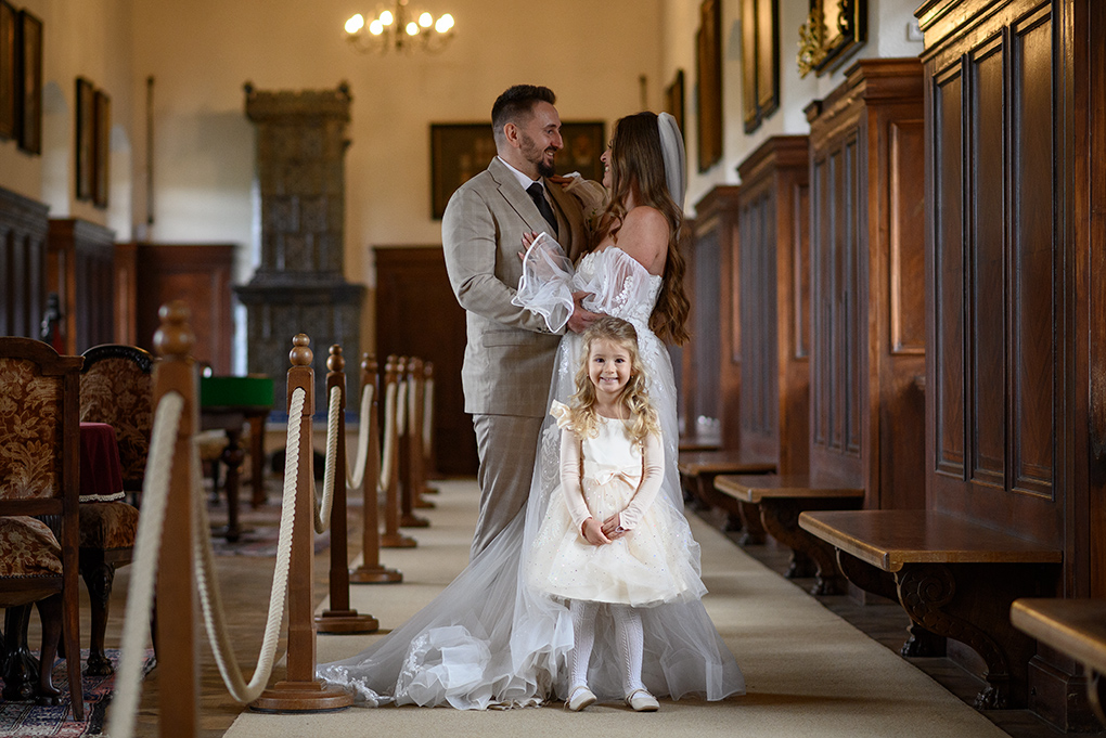 Pár s družičkou Mladomanželia s malou družičkou v historickej miestnosti.