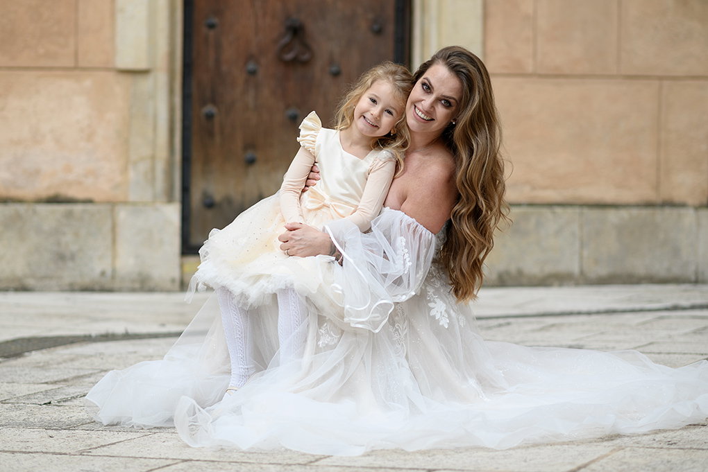 Nevesta s dieťaťom Nevesta sedí na zemi a drží v náručí malé dievčatko.