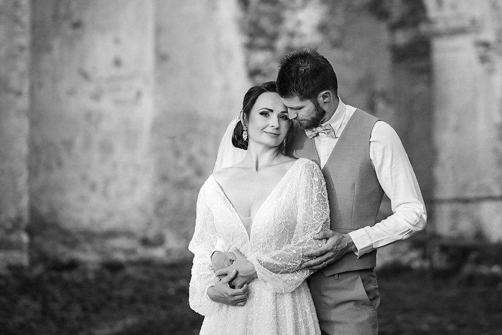 Čiernobiely portrét novomanželov v objatí pred historickými múrmi kláštora Katarínka.