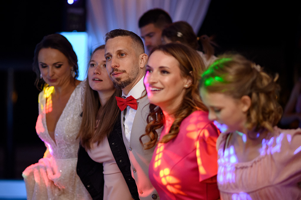 Nevesta a svadobní hostia sa držia za ramená počas spoločného tanca v Kerkira Pube.