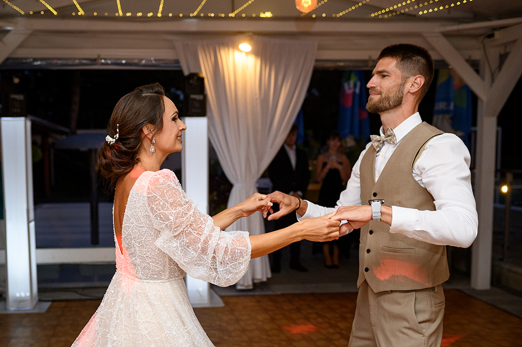 Novomanželia si užívajú svoj prvý svadobný tanec v krásne osvetlenej sále.