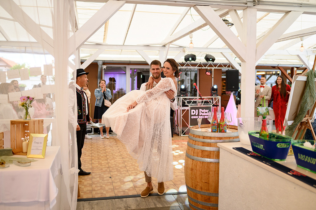 Ženích prenáša nevestu v náručí cez prah svadobnej sály v Kerkira Pub.