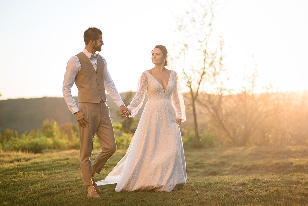 Svadobný pár kráčajúci po lúke pri kláštore Katarínka počas zlatej hodinky.