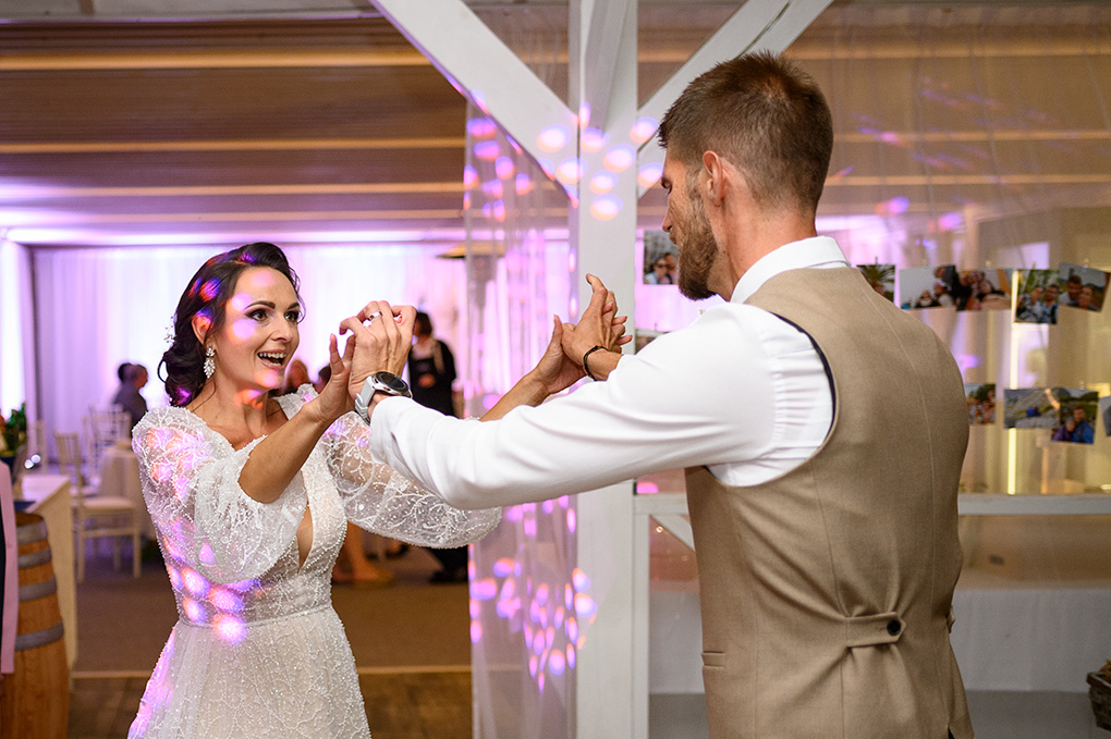 Vysmiata nevesta tancuje so ženíchom v obklopení svadobných hostí.