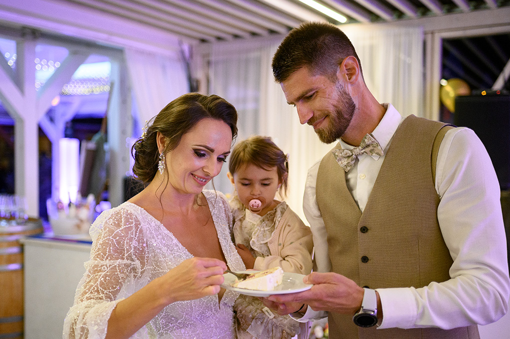 Detailný záber na mladomanželov, ako si vzájomne vychutnávajú prvý kúsok svadobnej torty.