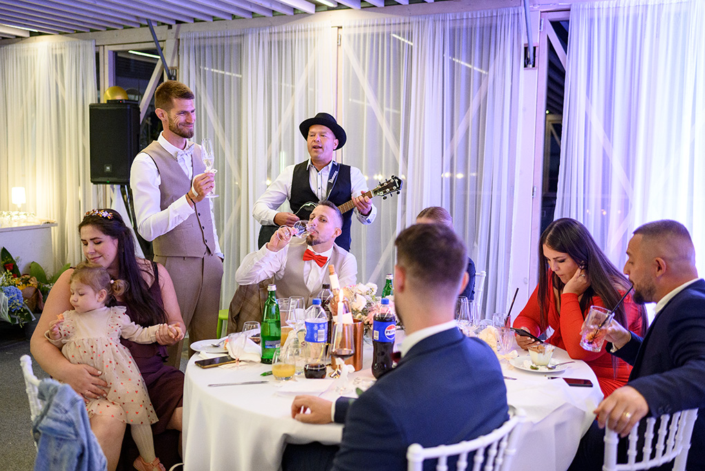Gitarista hrá hosťom priamo pri stole počas svadobnej večere.