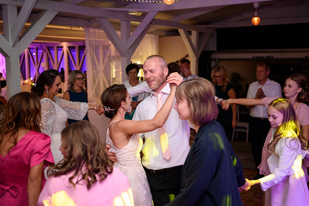 Svadobní hostia v kruhu tancujú s nevestou počas vyvrcholenia večera.